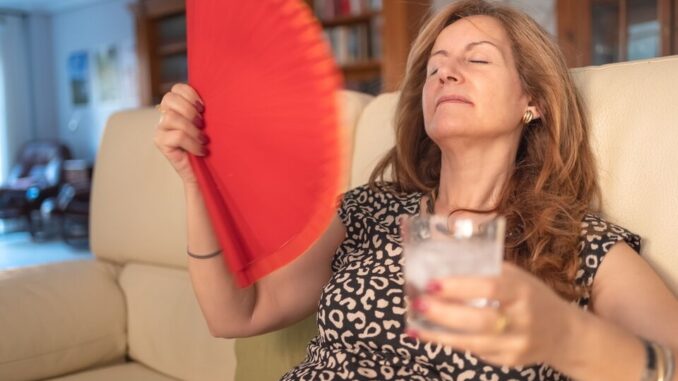 Woman,Giving,Herself,Air,With,A,Fan,And,A,Glass